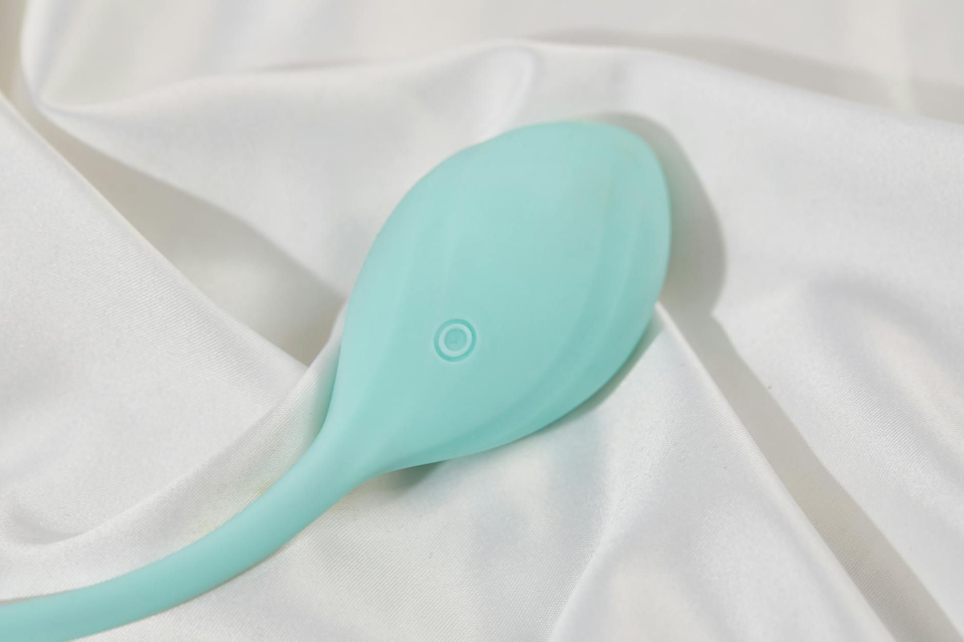 Teal clitoral vibrator on white silk showing different sensation patterns