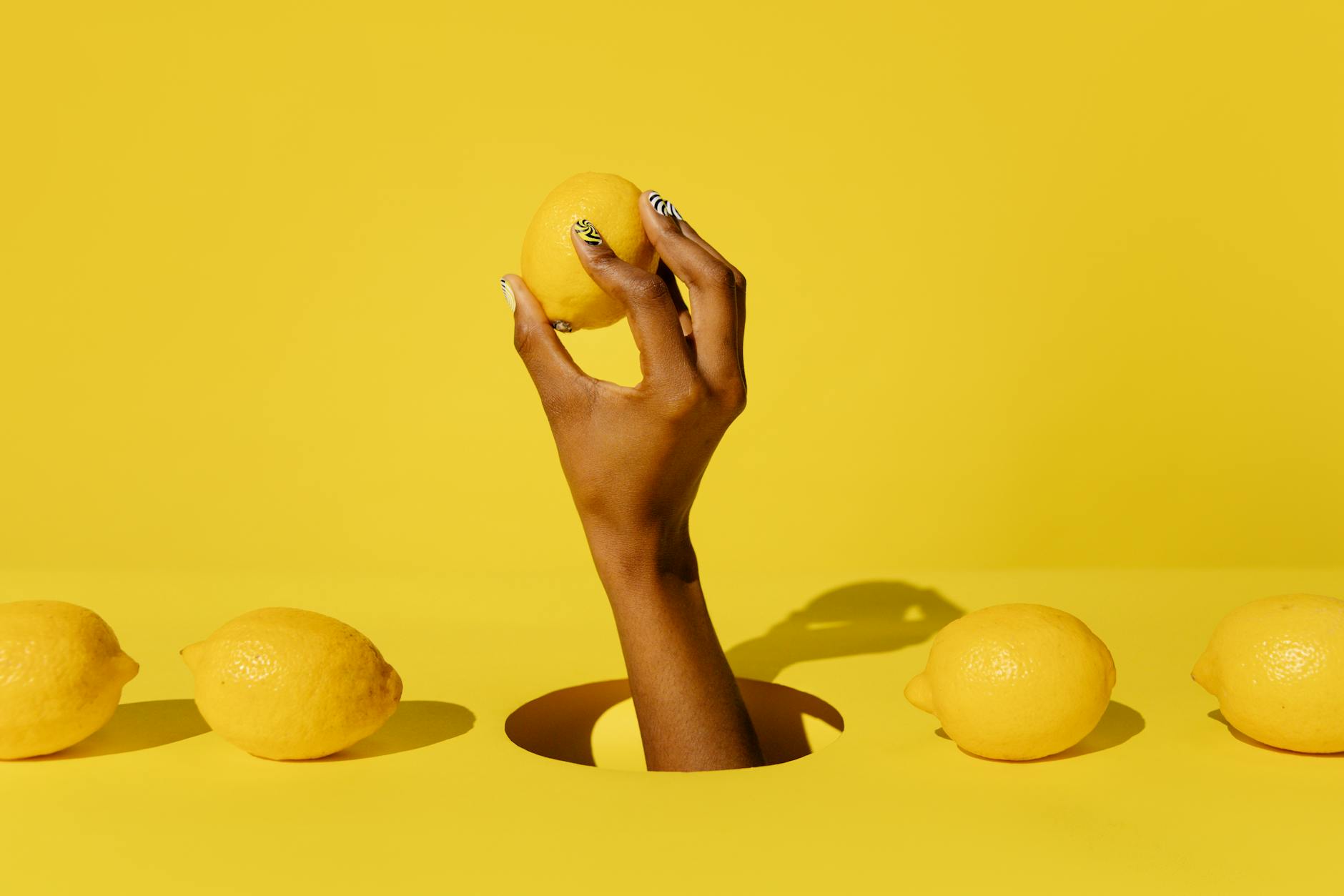 A hand holding an orange vibrator against a purple backdrop, modern and sensual