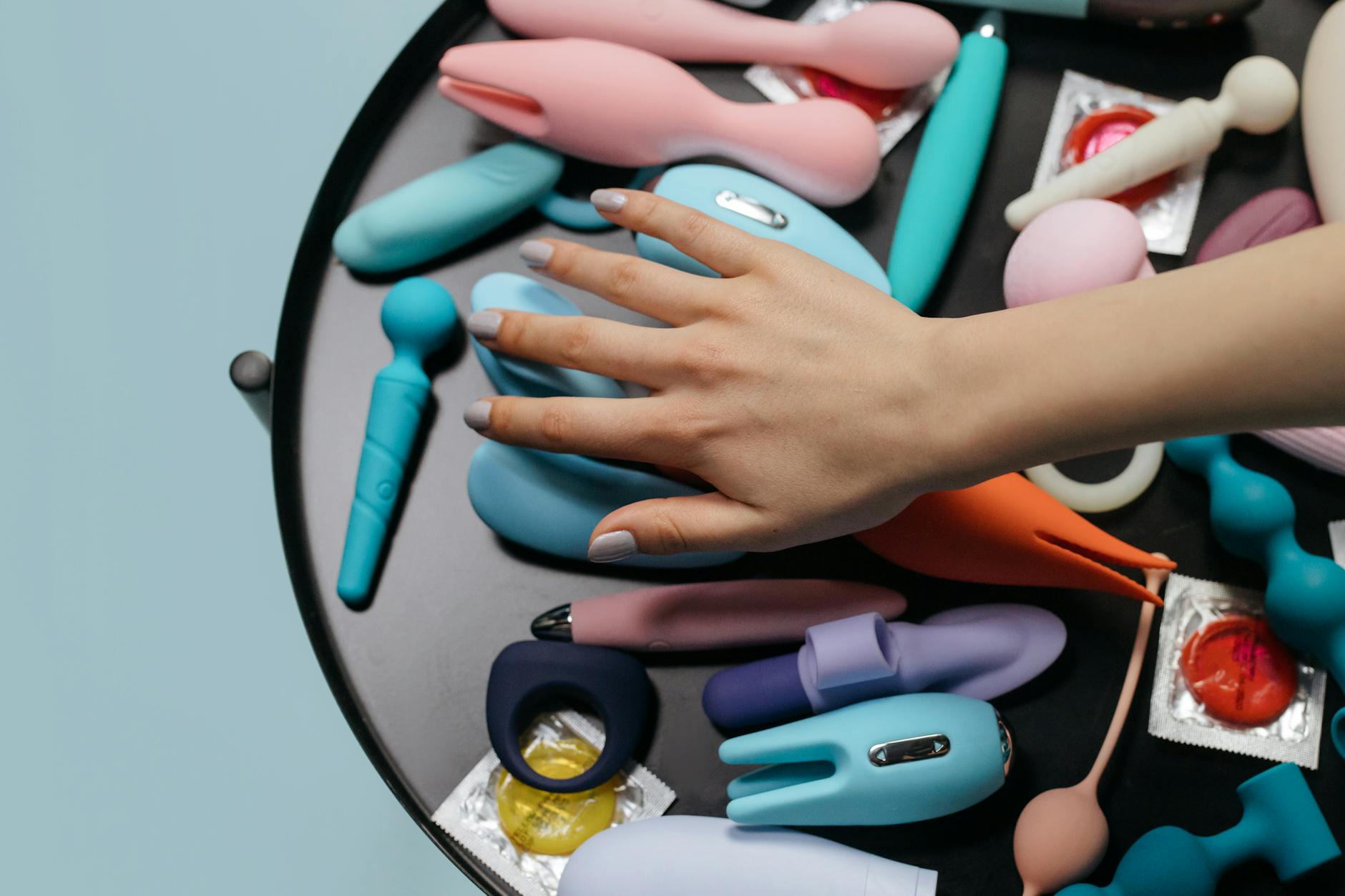 Vibrant display of colorful silicone clitoral vibrators and adult toys arranged on blue fabric