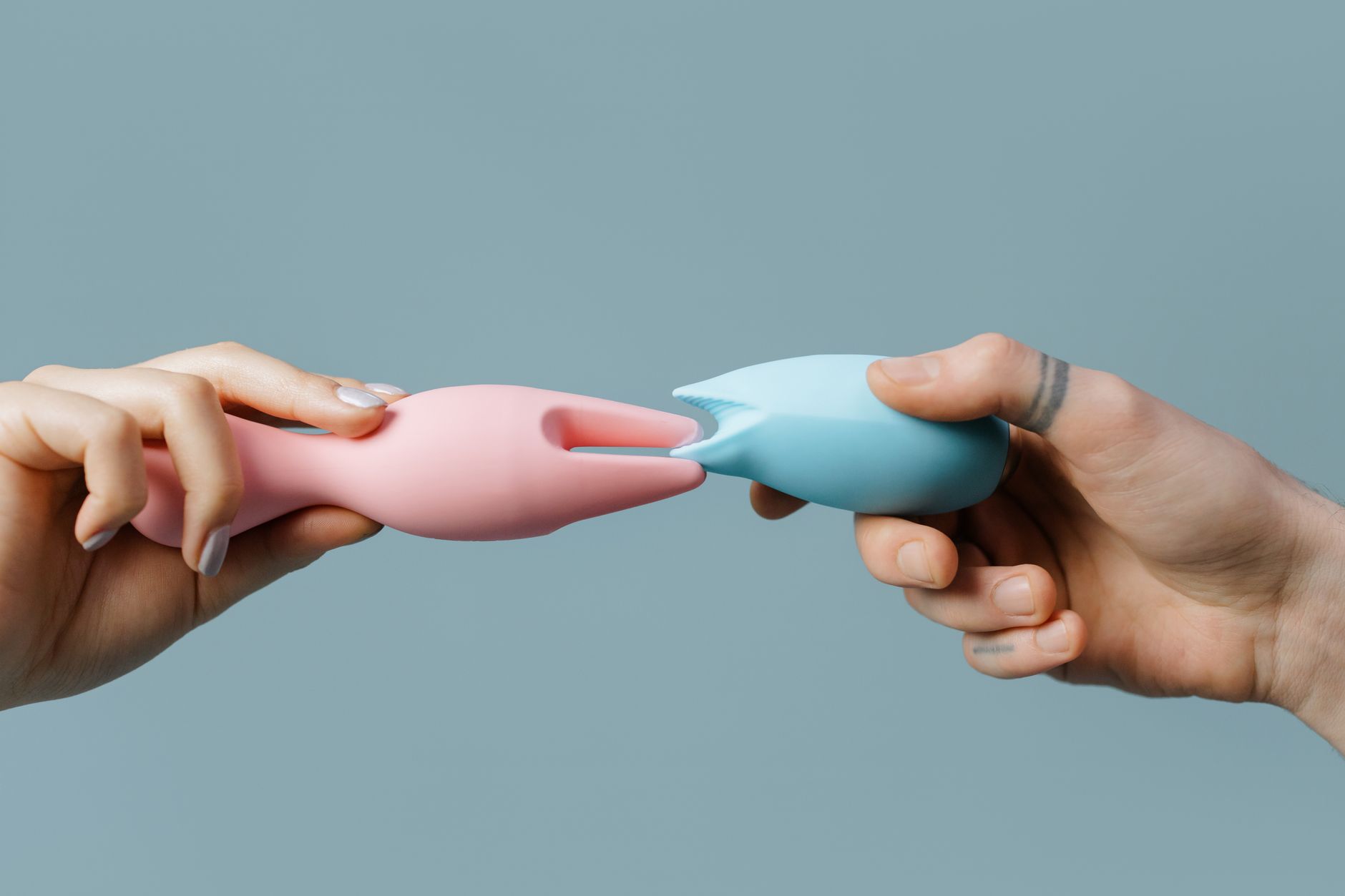 Hands holding colorful silicone toys, showing accessible pleasure tools