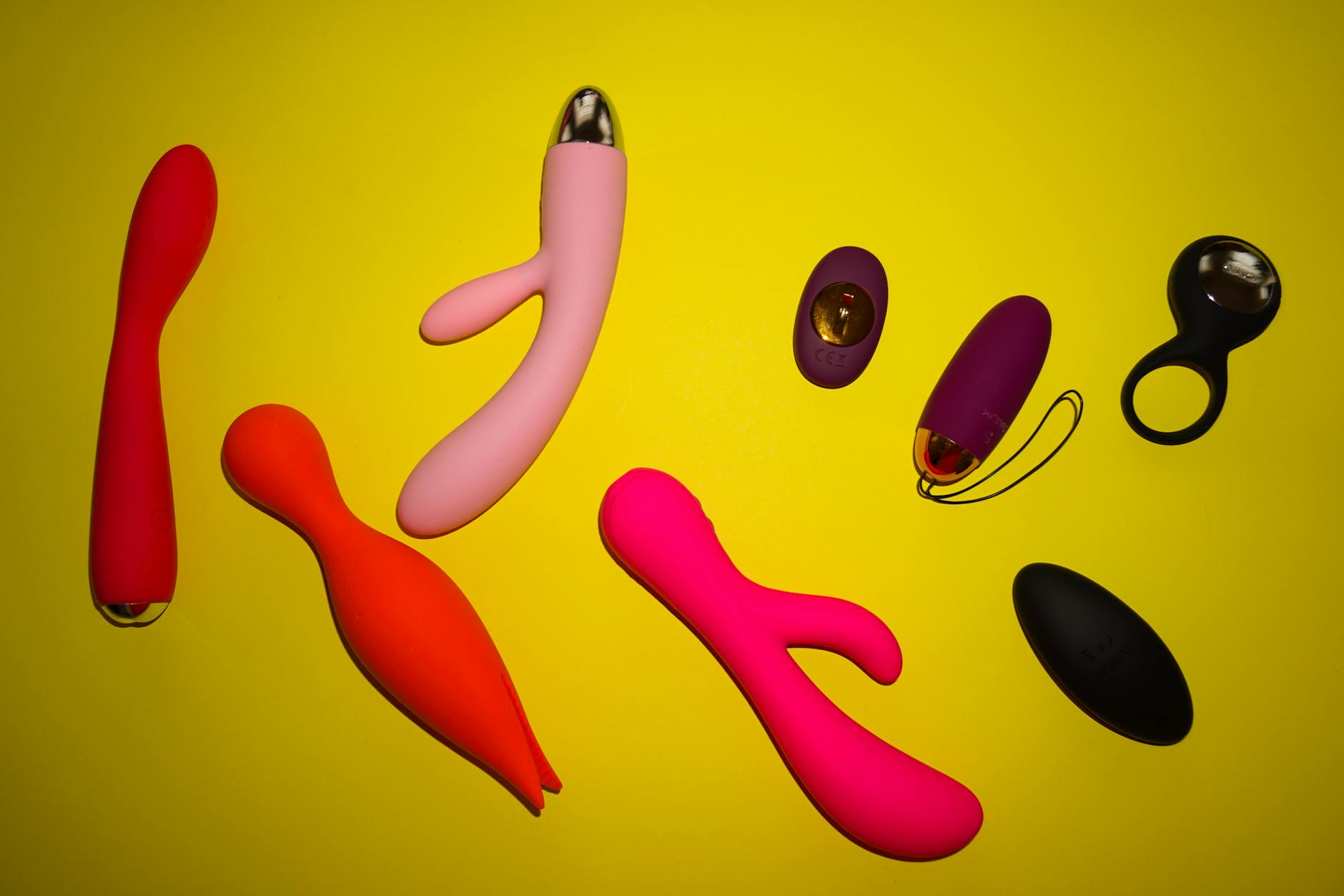 Vibrant arrangement of colorful clitoral vibrators on a bright yellow surface